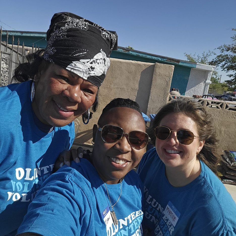 Three volunteers smile at a job site.