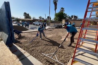 Volunteers spread gravel in the front yard of a residential home.