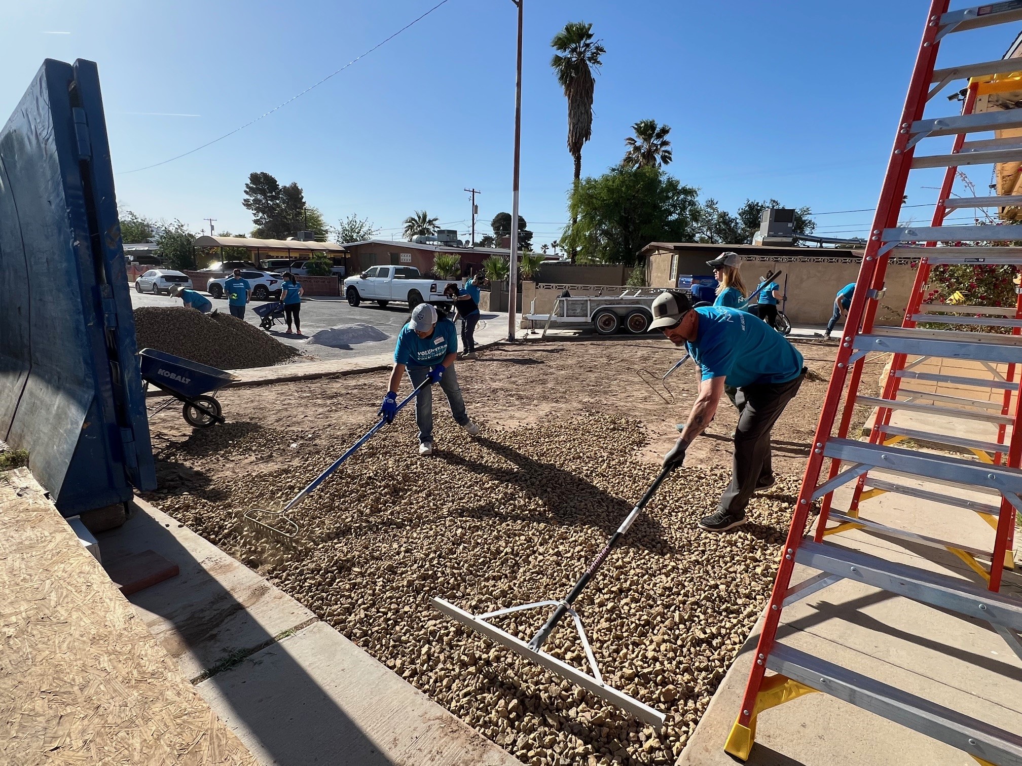 Volunteers spread gravel in the front yard of a residential home.