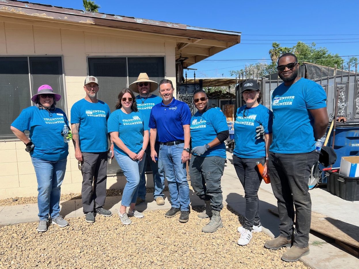 NNSS volunteers smile in the front of a residential home.