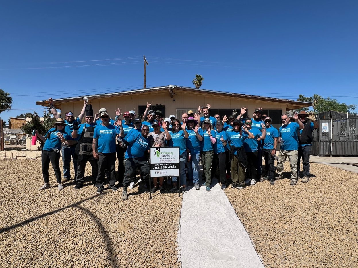 Volunteers stand in from of a newly landscaped home. 