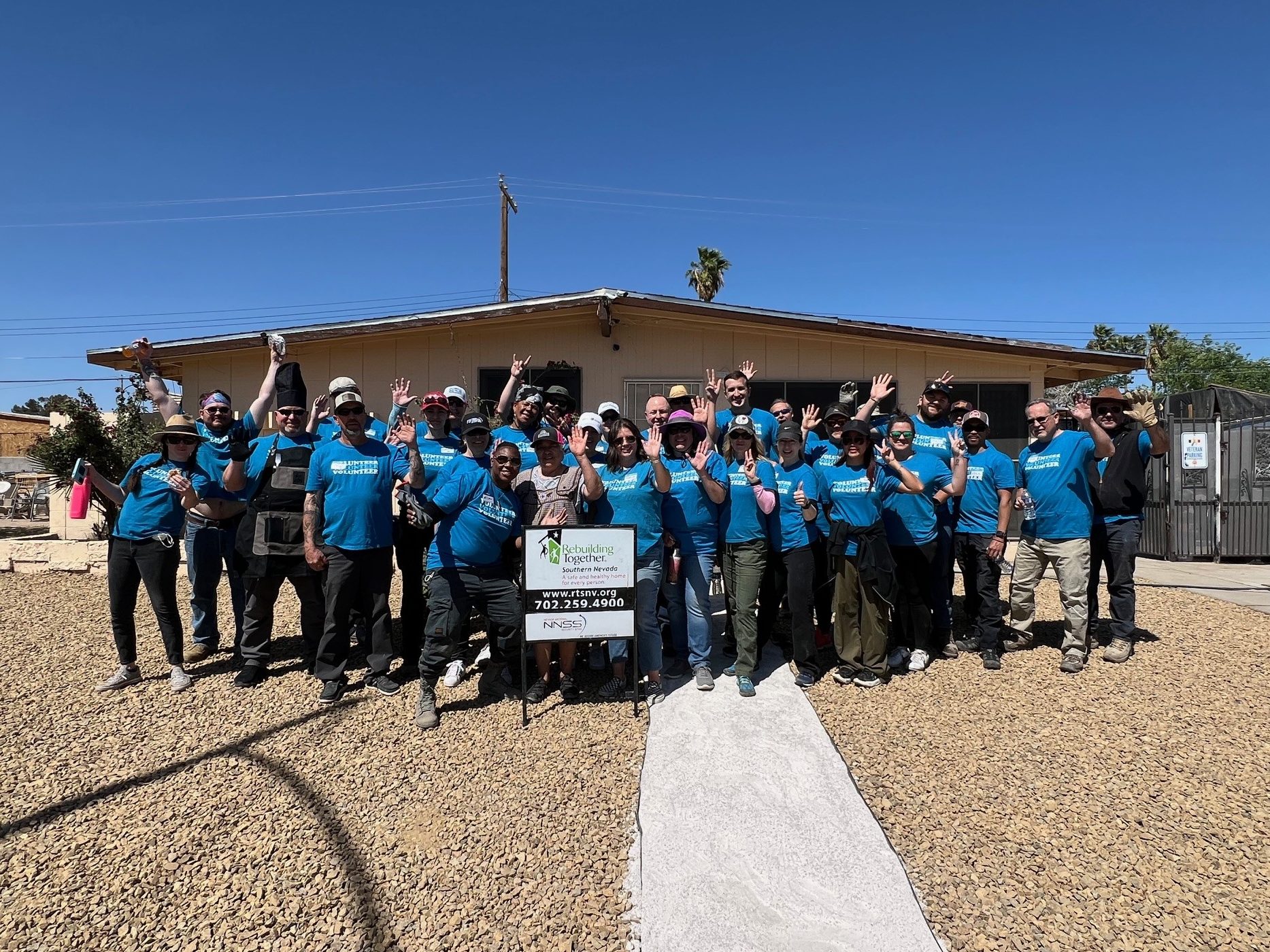 Volunteers stand in from of a newly landscaped home.