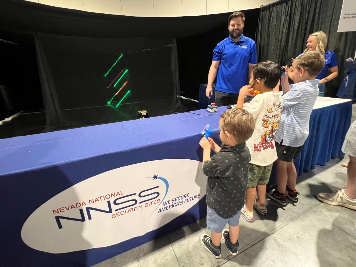 Three students watch lasers in motion.