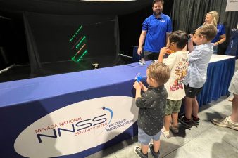 Three students watch lasers in motion.