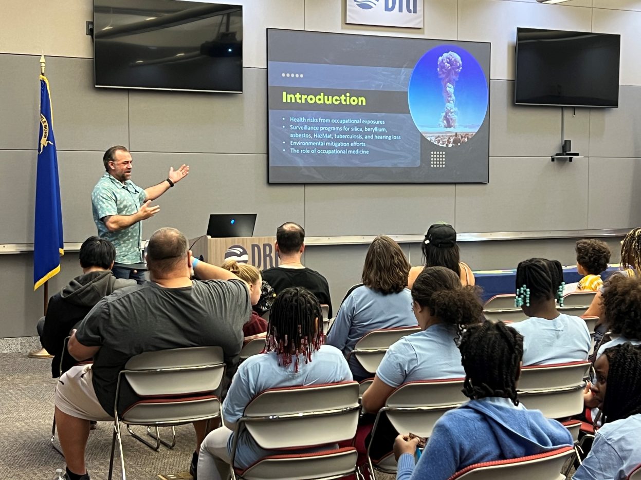 A doctor gestures to a presentation slide. 