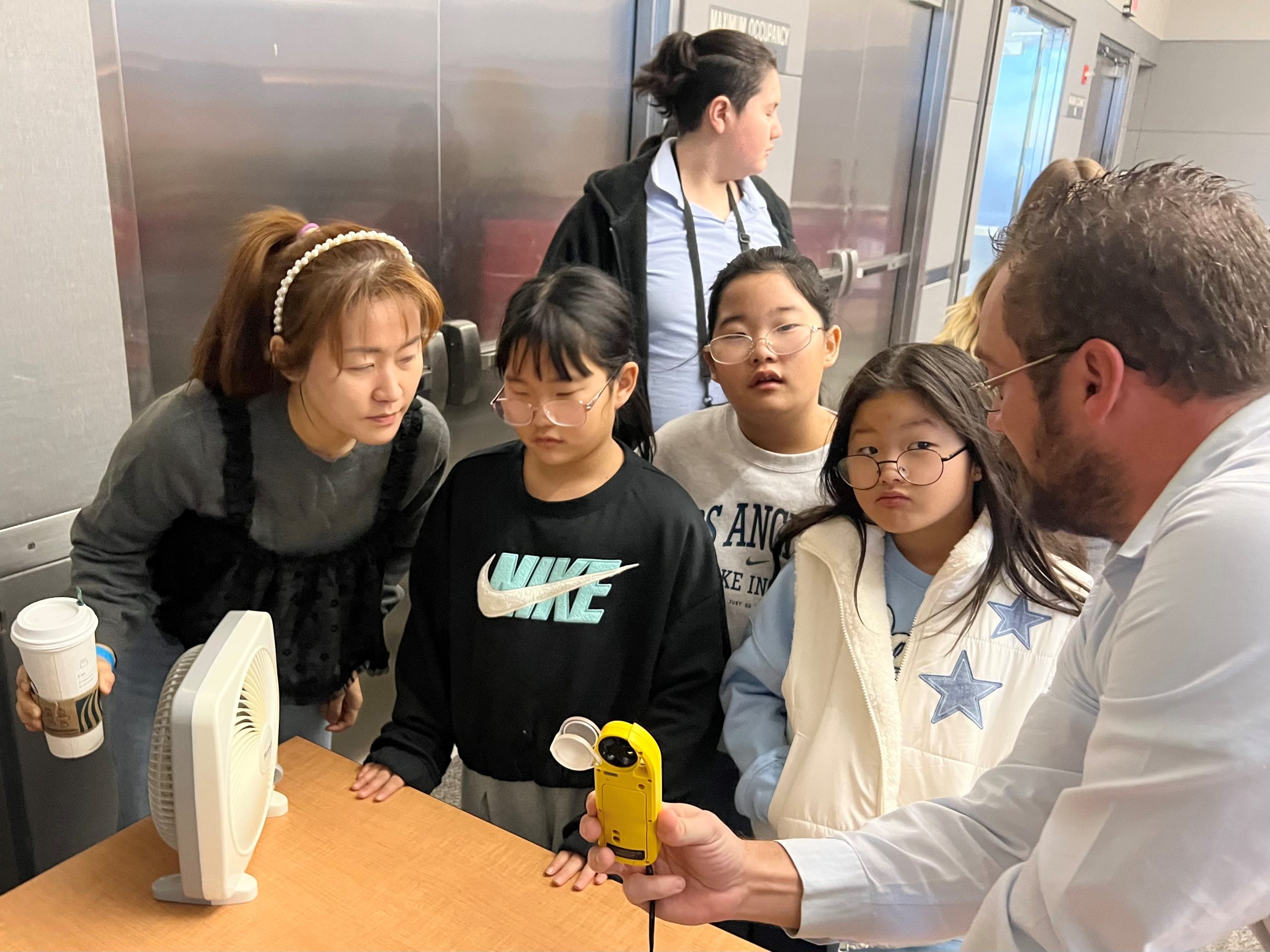 Students take a temperature reading in front of a fan.