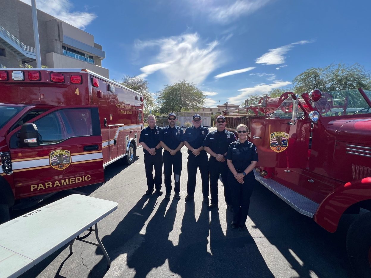 Firefighters stand between an Emergency Medical Services vehicle and a 1950 Seagrave engine.