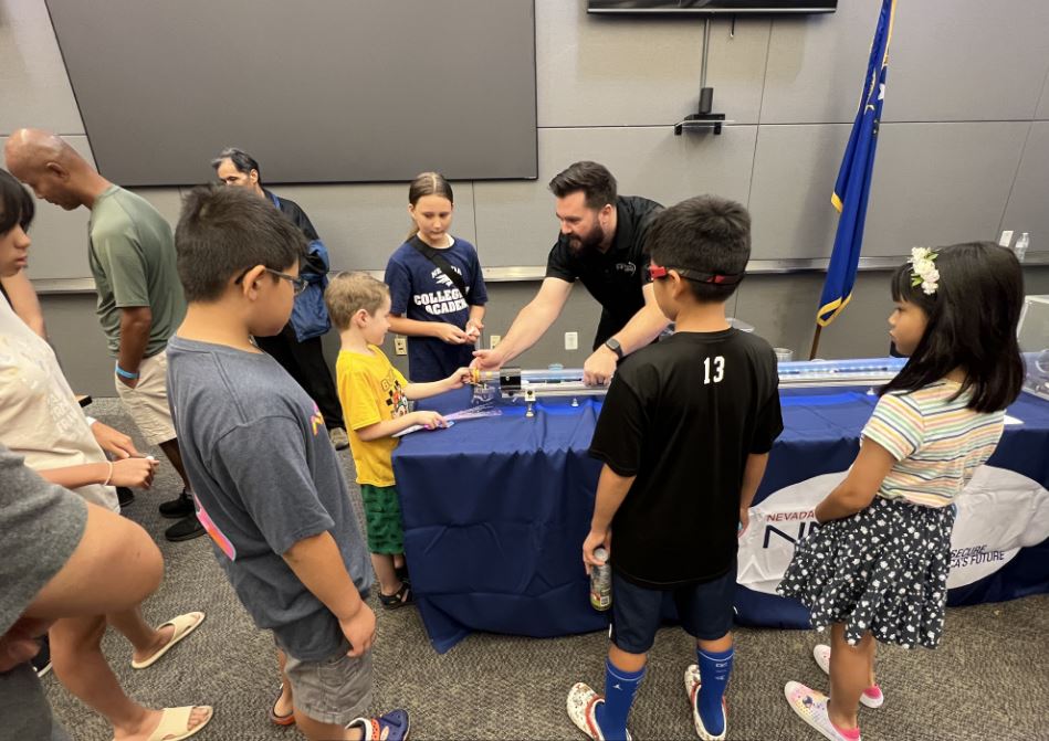 An engineer demonstrates a STEM activity to students.