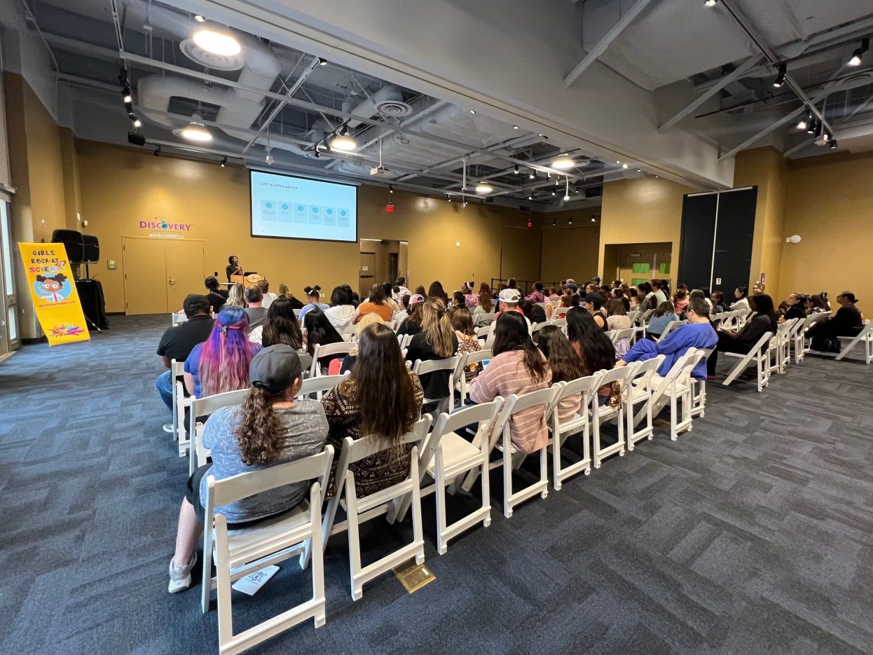 A seated crowd listens to a STEM presentation.