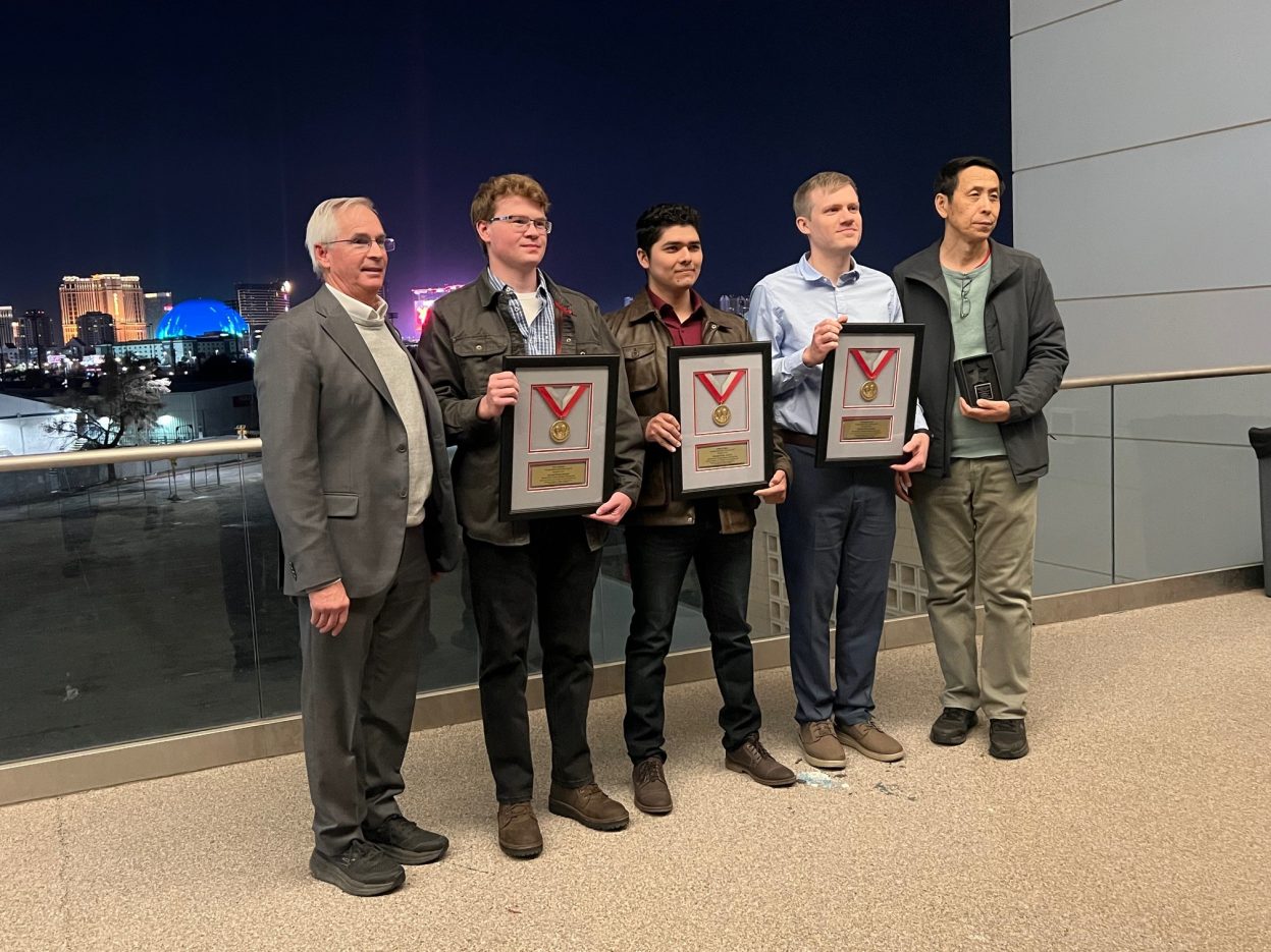 Students stand with framed awards with the Las Vegas Strip in the background.