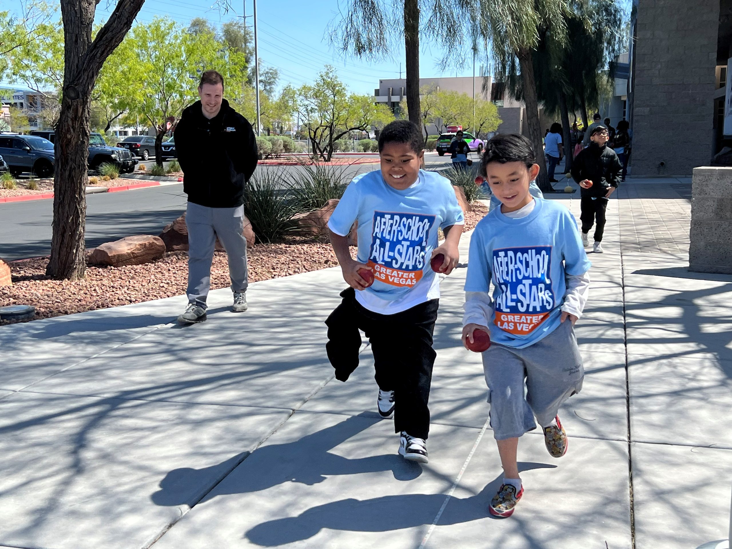 Two students run and smile in front of the Atomic Museum.
