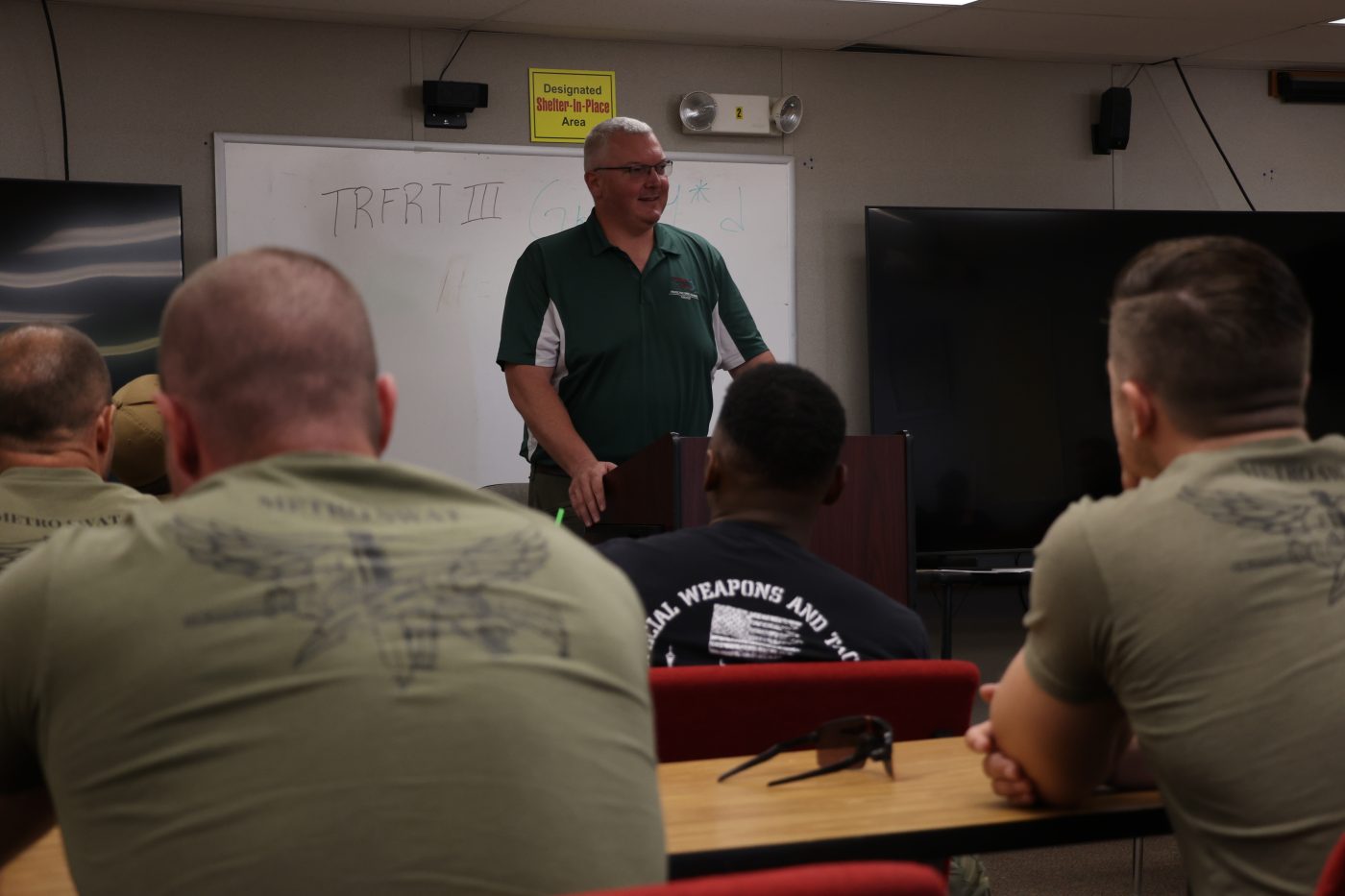 An instructor in front of a whiteboard addresses a classroom.