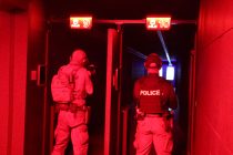 Two men in tactical gear stand in lanes with red lighting.