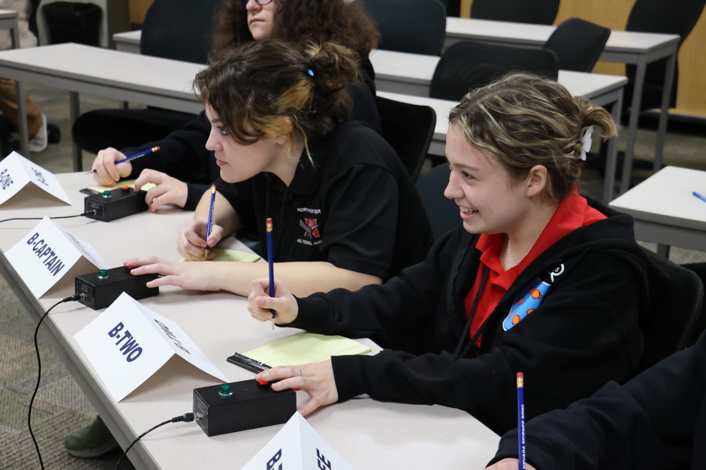 A student presses a buzzer to answer a trivia question.