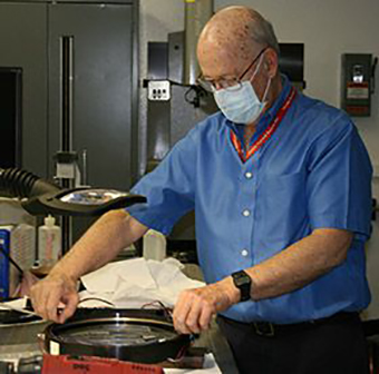 A man adjusts a laboratory lens. 