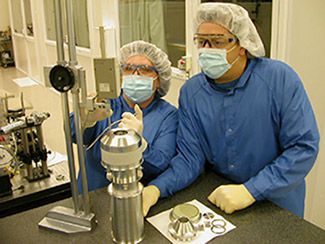 Two scientists in a lab wearing PPE and working on a steak tube.