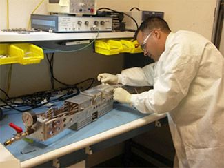 A man in a white laboratory coat works on a Gated X-Ray Detector.
