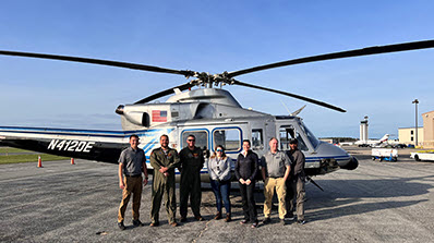 Seven team members standing in front of the Bell 412 helicopter