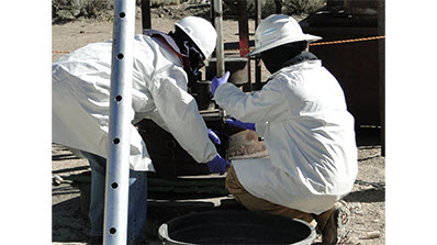 Technicians collect samples from a groundwater well at the NNSS