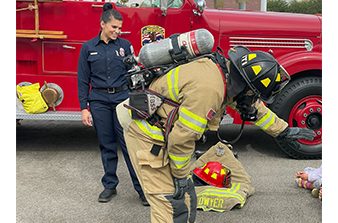 Firefighter in full turnout interacting with students