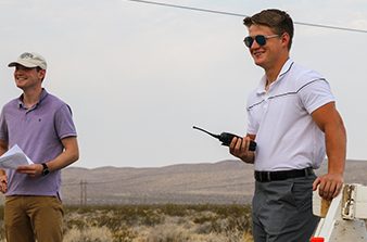 Alex Carter holding paperwork and Luke Lhota holding a radio while performing duties during a rocket launch at the Site.