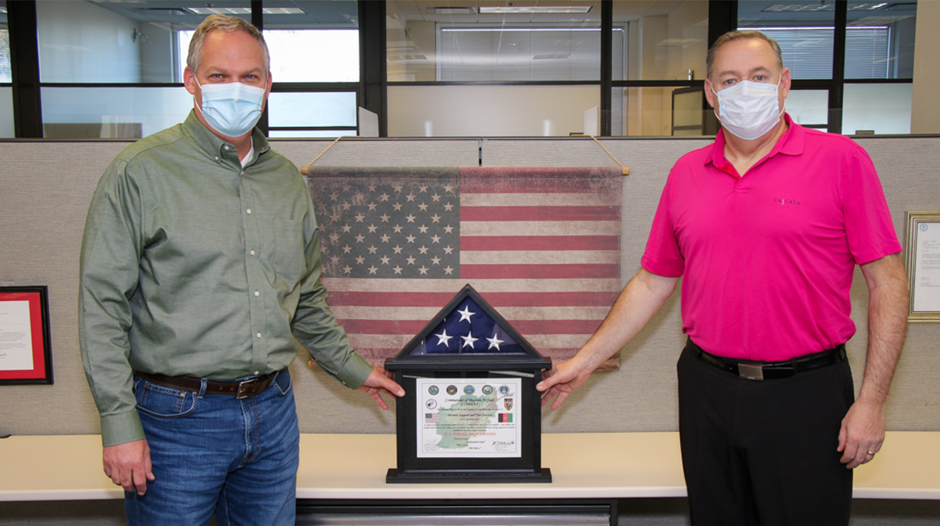 NNSS Stockpile Experimentation & Operations Senior Director J.C. Wallace (left) and Program Director of Transformation Rodney Rego with the presented flag and certificate.