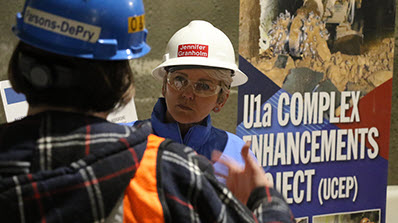 Energy Secretary Jennifer Granholm in a hard hat receiving a briefing at the U1a Complex