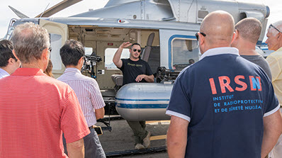 NNSS pilot Mike Toland (center) shares his experience flying the NNSA’s twin-engine Bell 412 helicopter in extreme conditions and urban environments during the 10th annual AMS technical exchange.