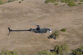 black drone in flight over desert