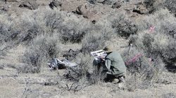 worker squatting in desert area of NNSS to record data