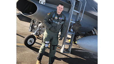 Jeremy Cunningham in flight suit in front of military plane