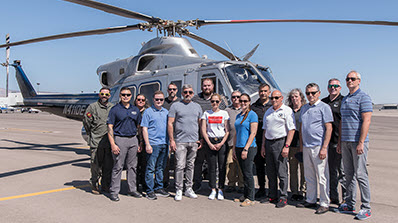 a group of people posing in front of a Bell 412 helicopter