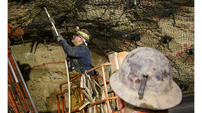 miner underground at U1a working on tunnel ceiling