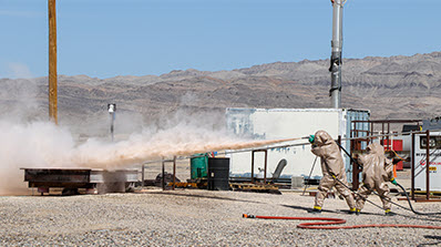 students in protective suits spraying a powder-like substance from hoses