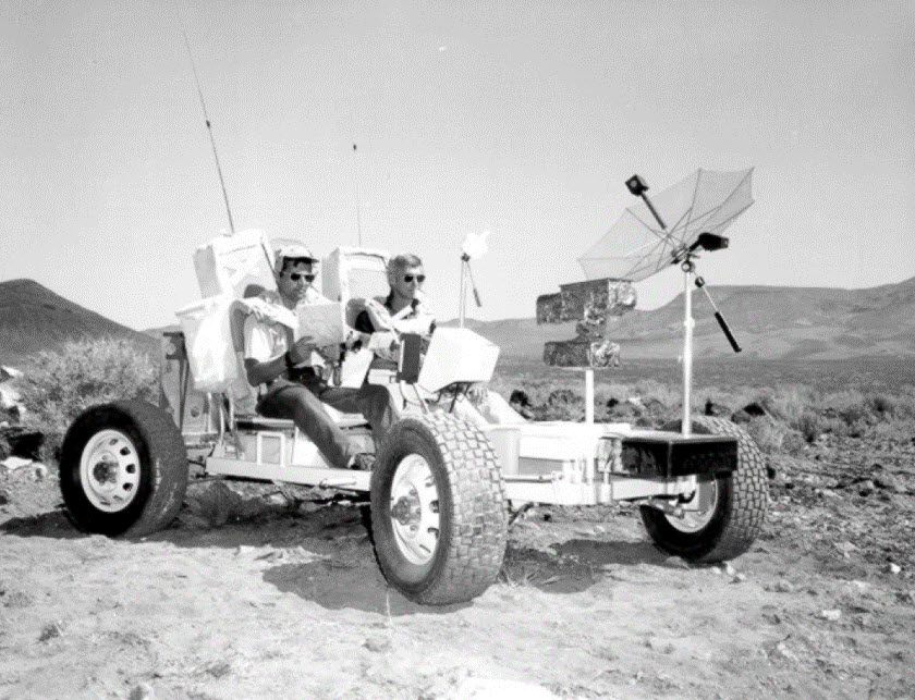 black and white photo of two men in Apollo lunar training vehicle in desert at the Site