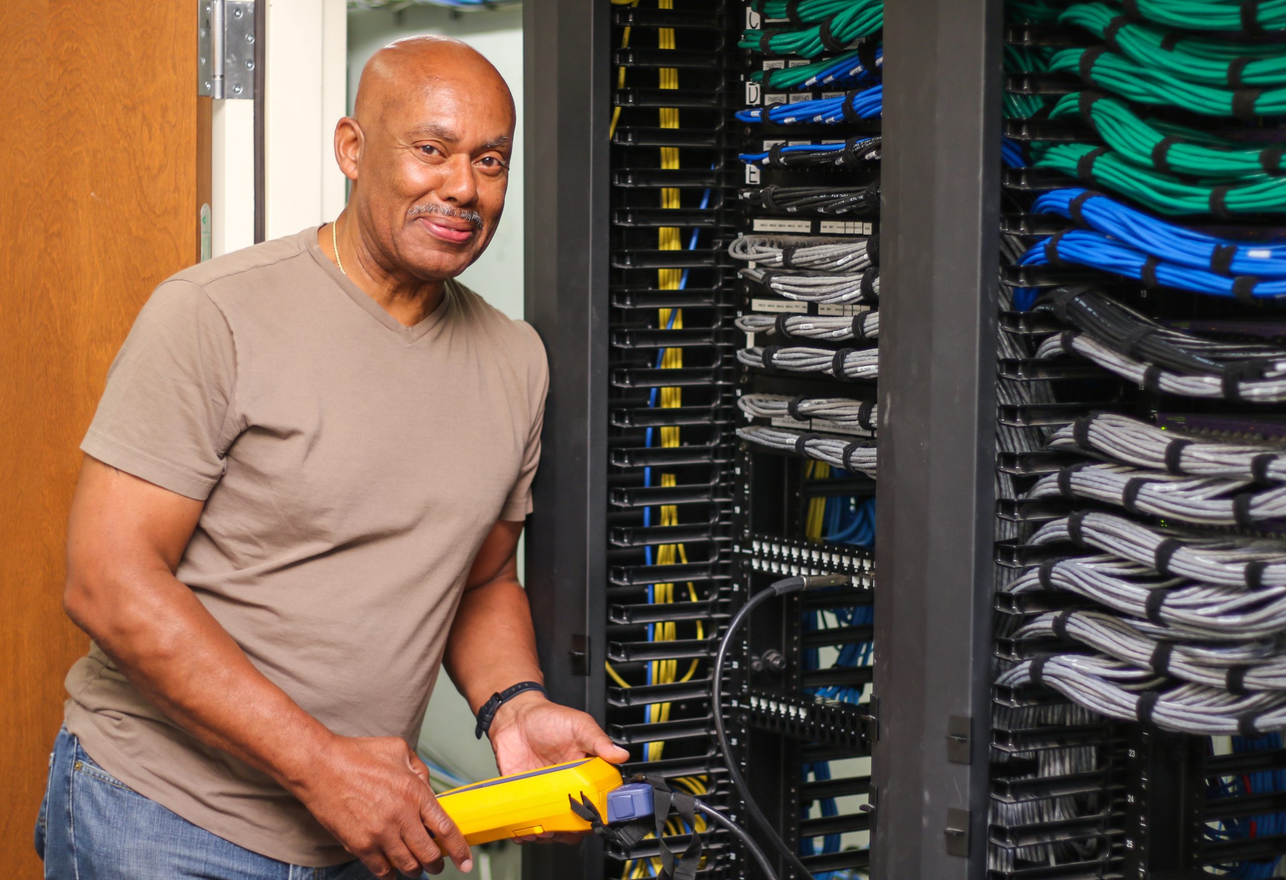 man in brown shirt standing next to IT panels