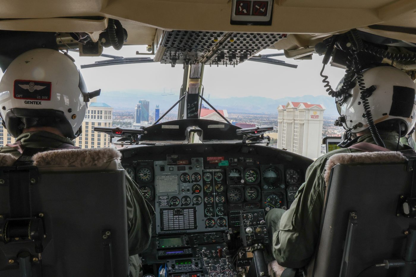 photo from inside helicopter looking out the front with a view of the Las Vegas strip with pilots to either side