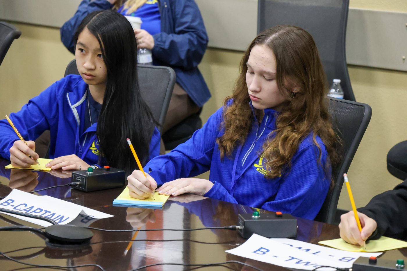 two female students in blue jackets sitting at a table waiting for a question during Nevada Science Bowl competition