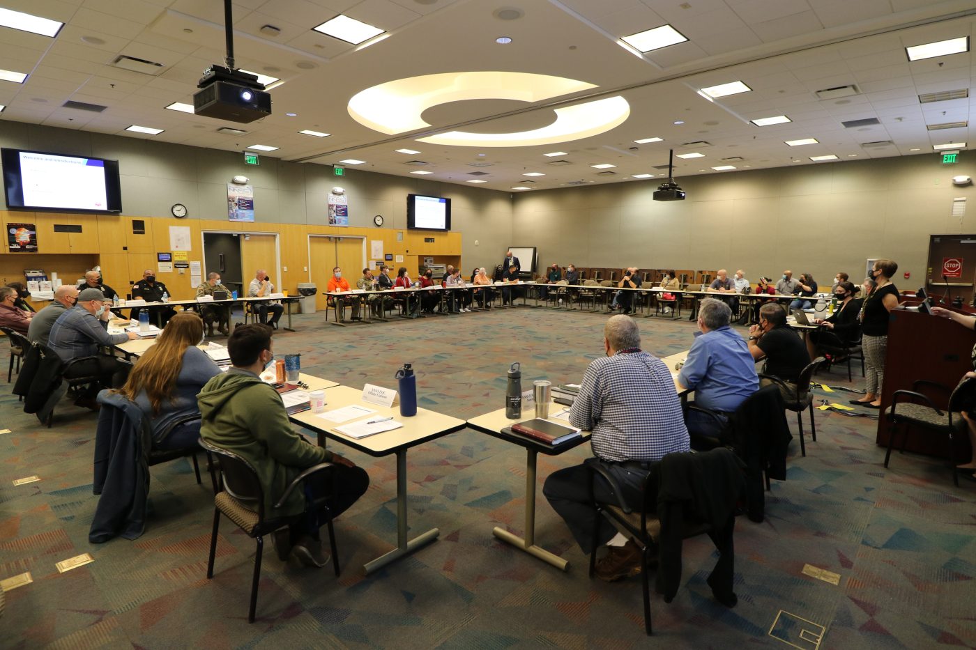 large room with tables in a circle and people at the tables during an exercise