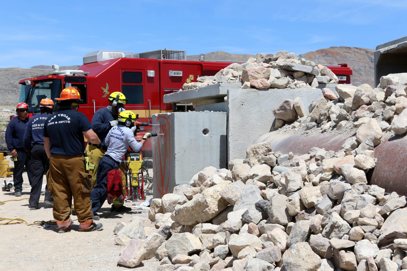 exercise scene of earthquake with rocks everywhere and rescue team trying to drill through a concrete wall