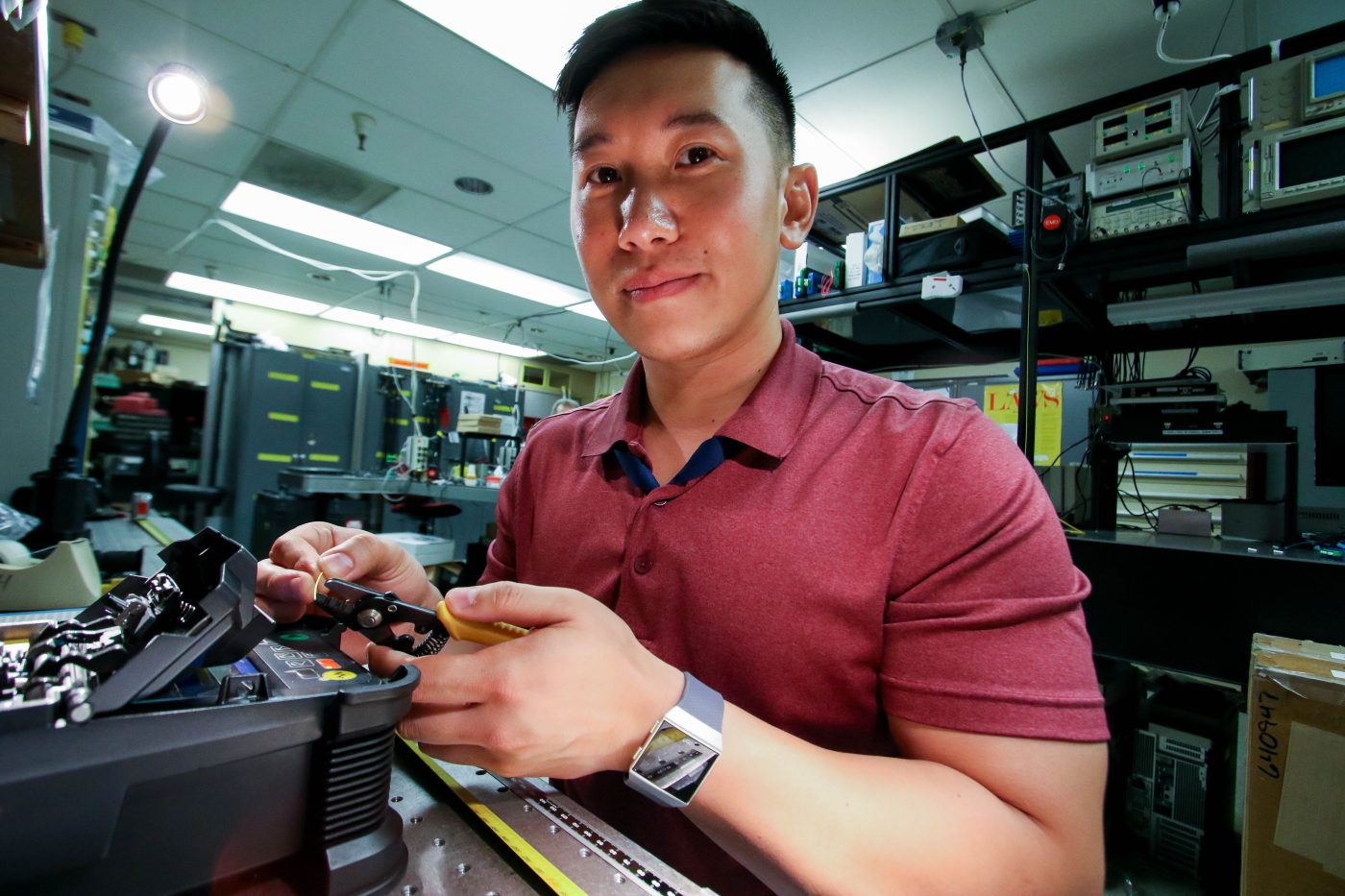 man with dark hair and red shirt holding technology