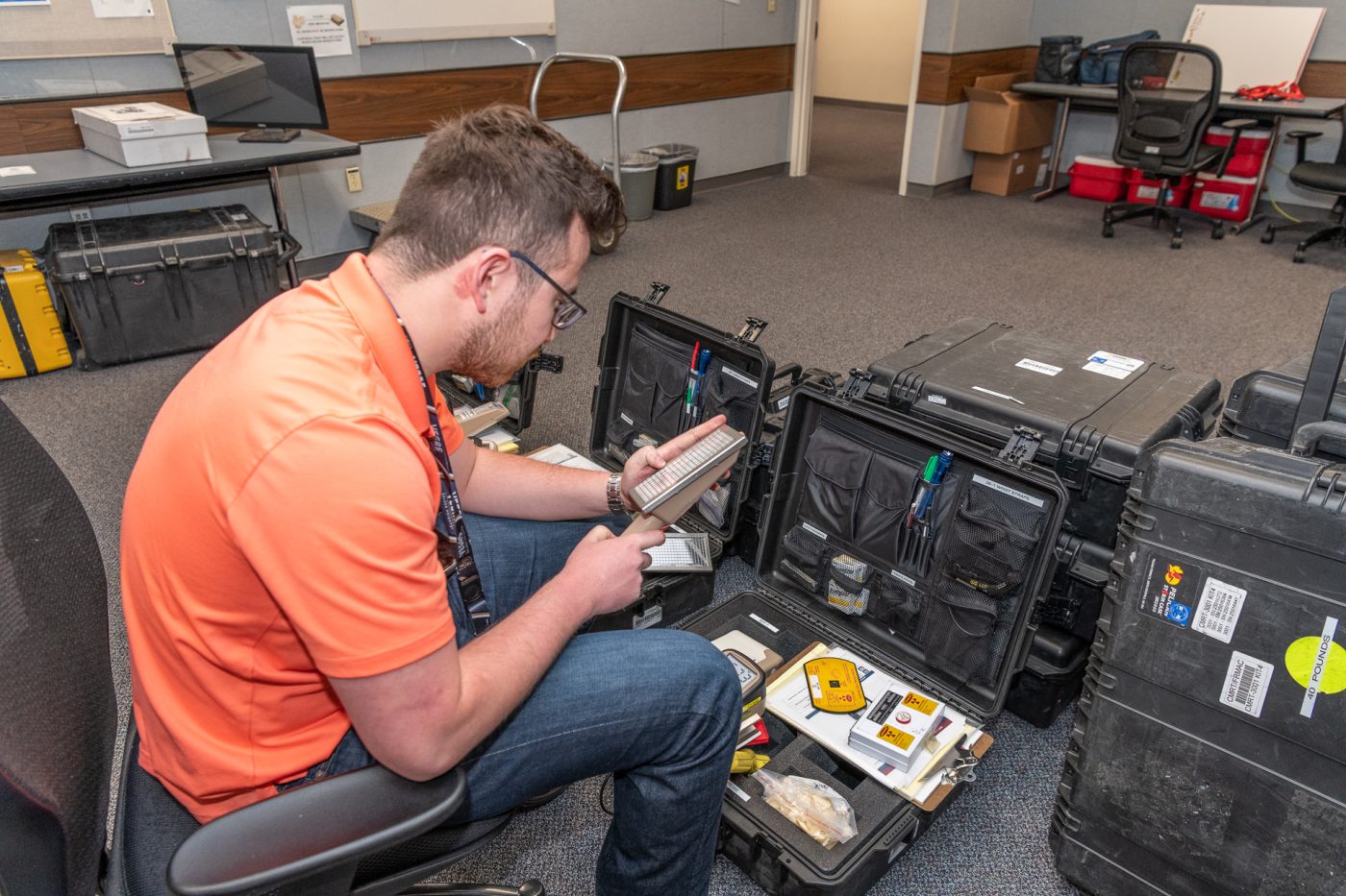 An RSL team member in an orange shirt prepares equipment for transportation.