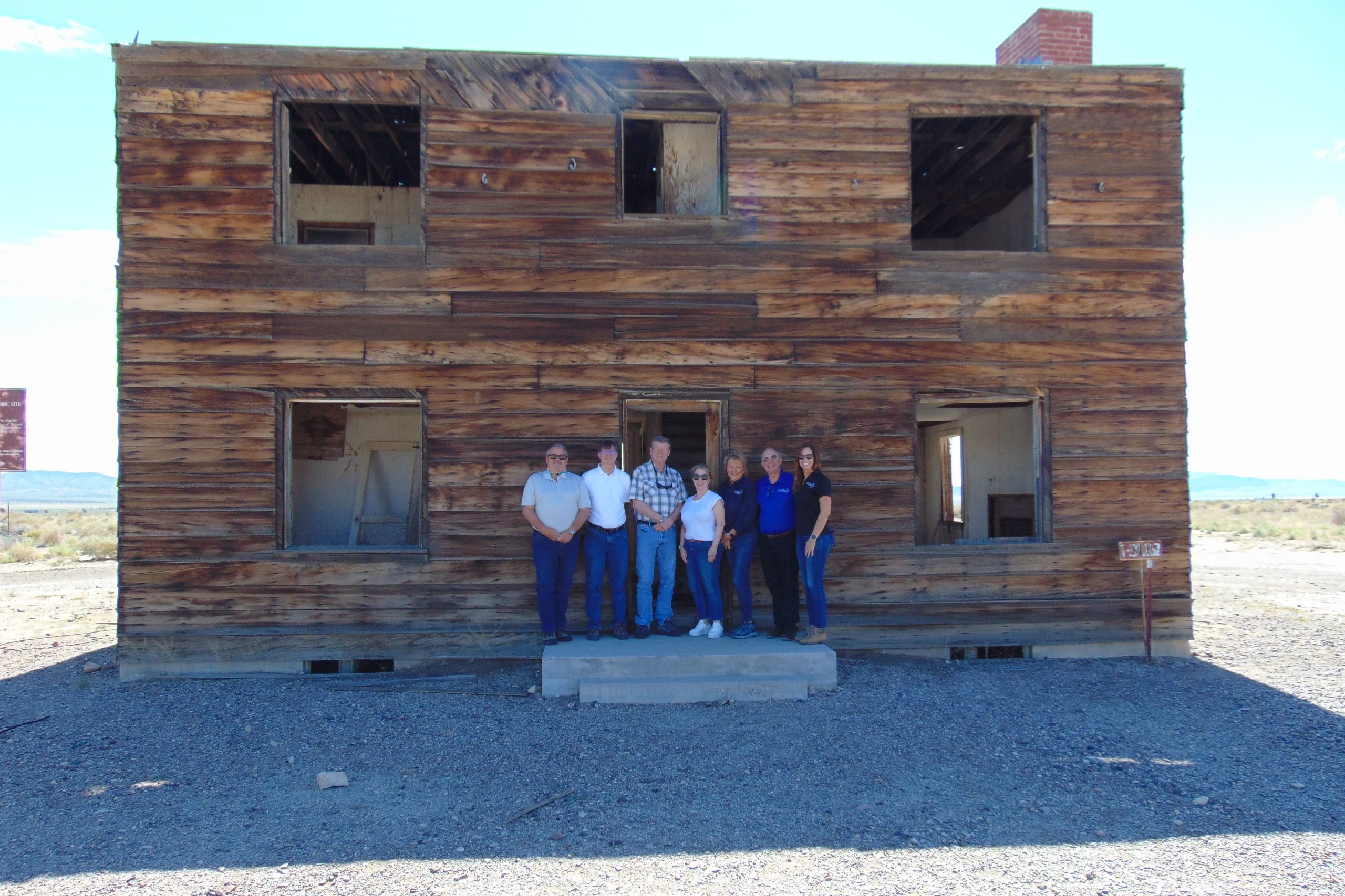 group of seven people posing in front of the Apple 2 house at the NNSS