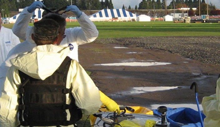 A man in personal protective equipment walks toward a response area.