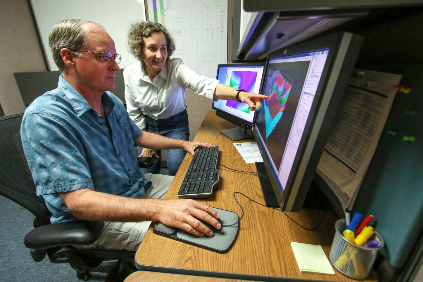 A man and woman consult a computer monitor.