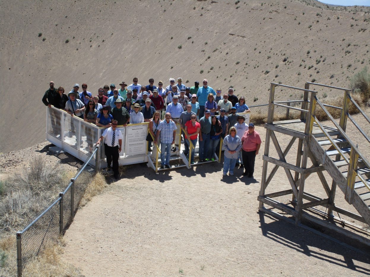 group of people standing on a platform in front of Sedan Crater at the NNSS