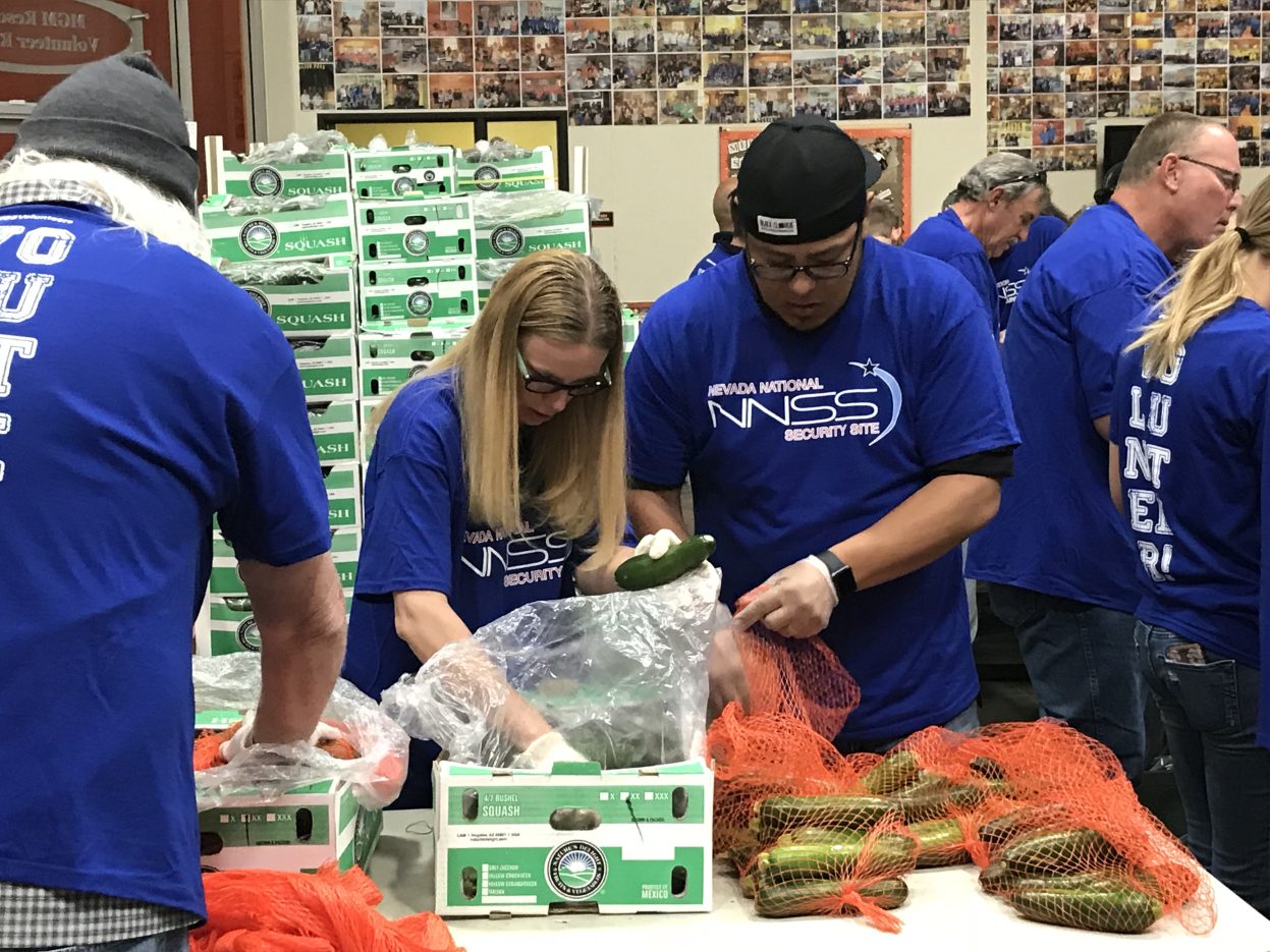 volunteers in blue shirts packaging food at Three Square food bank