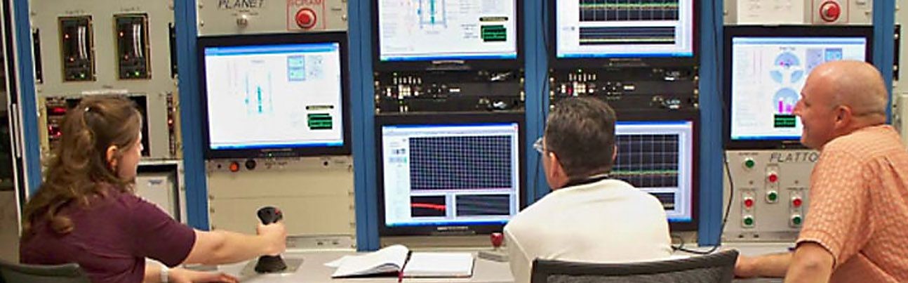 Three employees view data monitors.