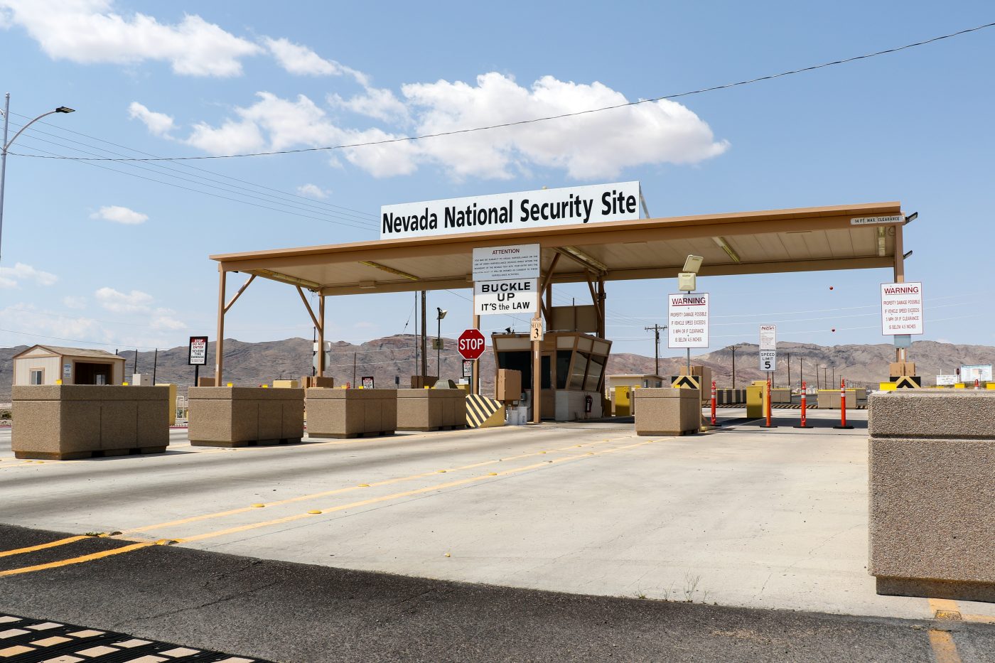 A road leads to the entrance gate of the Nevada National Security Site, where vehicles stop for a security checkpoint.