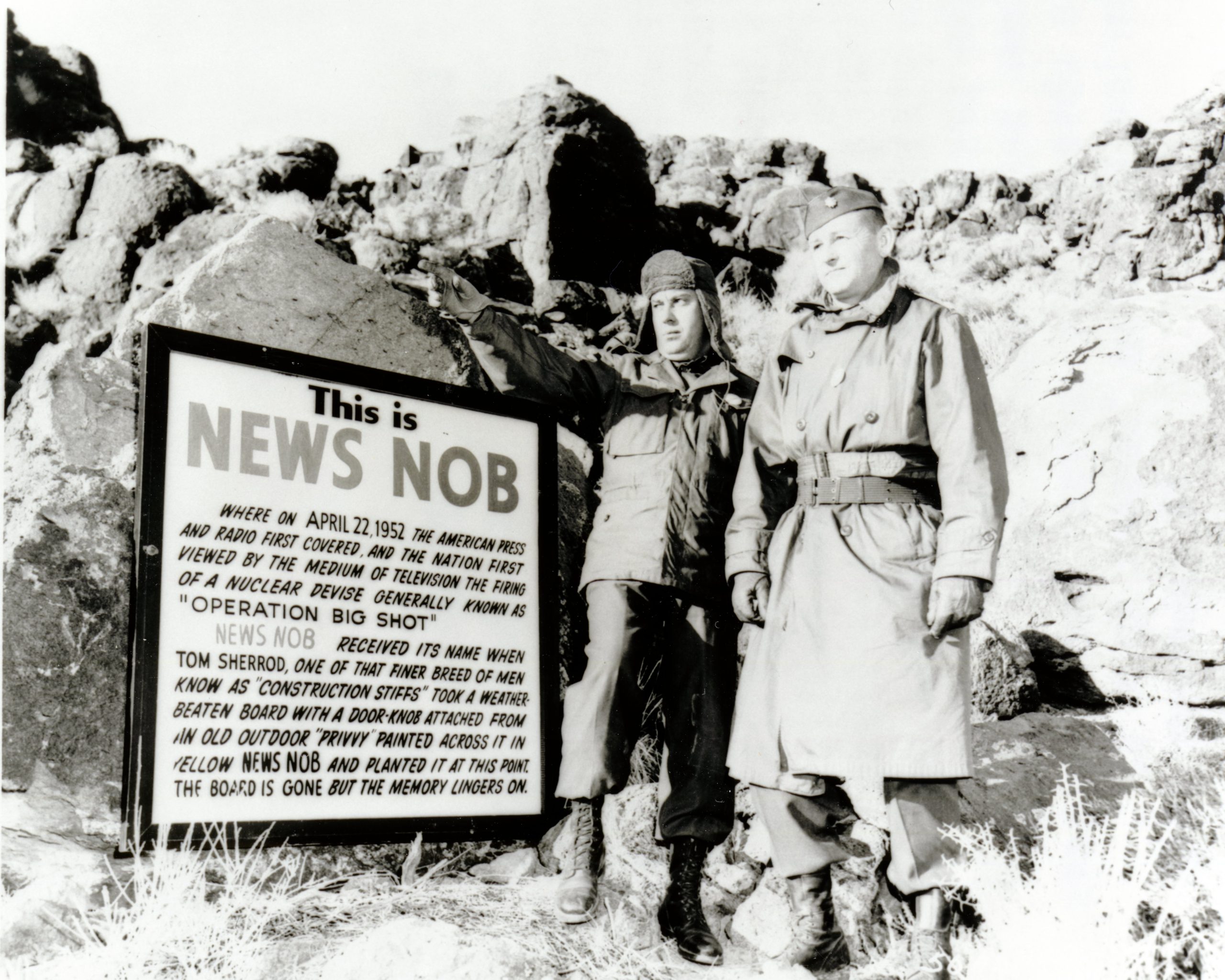 Two men stand near a sign that marks where reporters witnessed an atmospheric test on April 22, 1952.